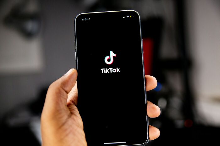 Person holding a phone displaying the TikTok app, illustrating discussions about kaomojis and cultural appropriation.