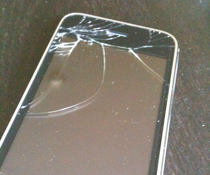 Cracked iPhone screen close-up showing damage after baby breaks friend&rsquo;s phone and Gucci sunglasses.