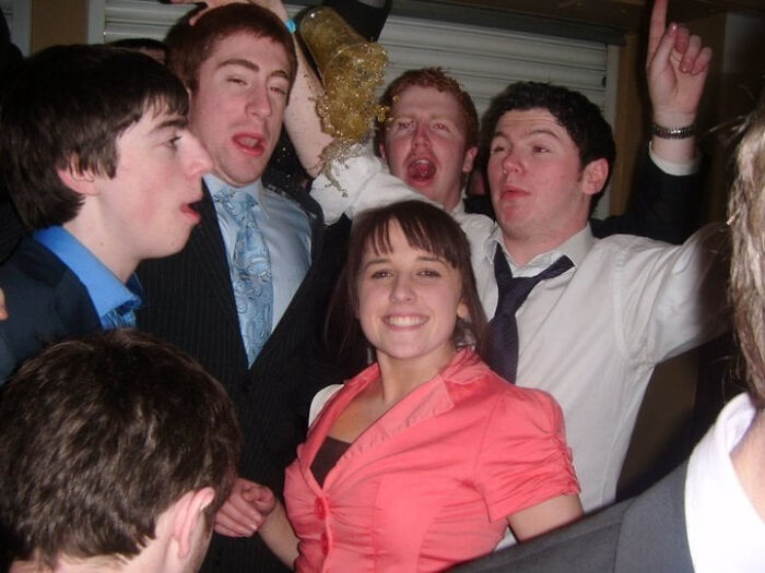 Group of young people at a party captured moments before a drink spills, showing the split second before disaster hits humorously.