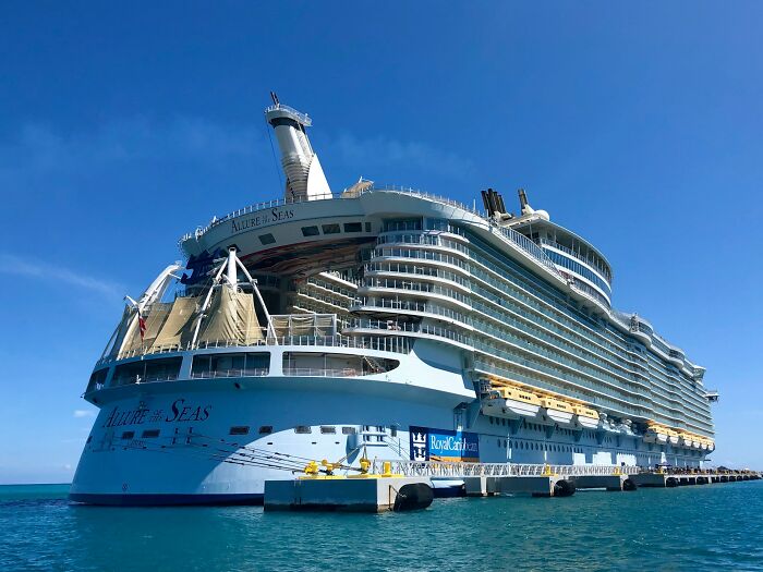 Large luxury cruise ship docked at a pier under clear blue skies, illustrating traveling to the Bahamas.