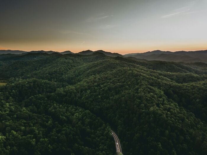 Aerial view of lush green forested travel destination with winding road at sunset, one of 57 travel destinations seen in person.