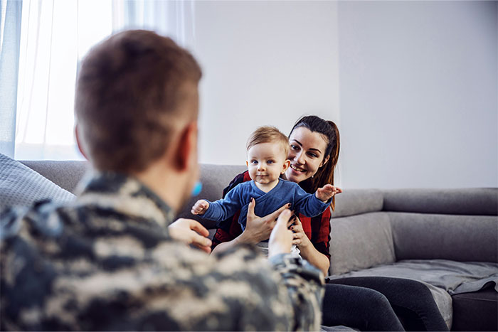A mother and soldier father playing with their baby at home, illustrating unexpected ways people found out their partner was cheating.