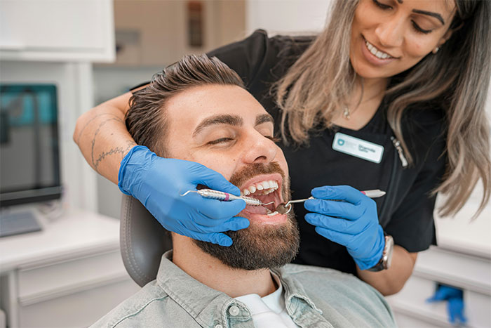 Man at dentist appointment with hygienist examining teeth, illustrating crazy and unhinged ways to find cheating partners.