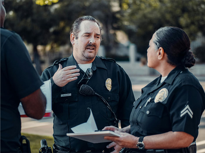 Two police officers discussing notes outdoors, illustrating crazy and unhinged ways people found out their partner was cheating.