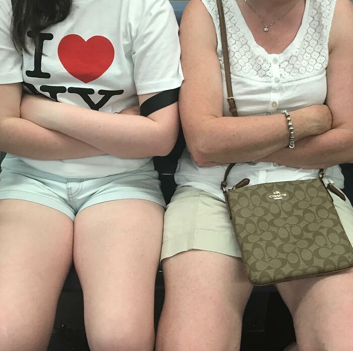 Two people sitting on the subway in New York, each carrying unique and interesting items in their hands.