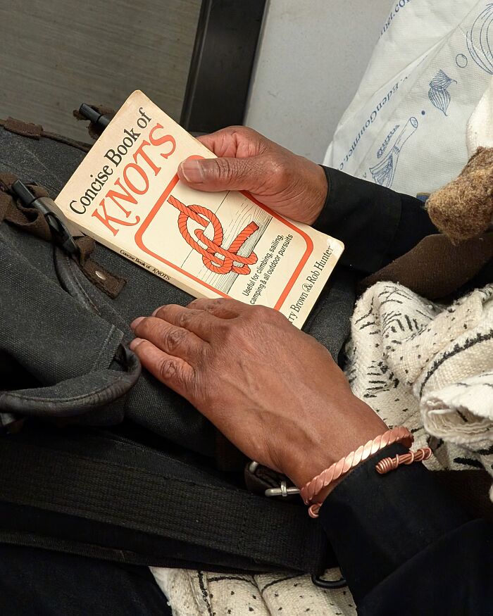 Person on New York subway holding a book about knots, showcasing unique and interesting items in their hands.