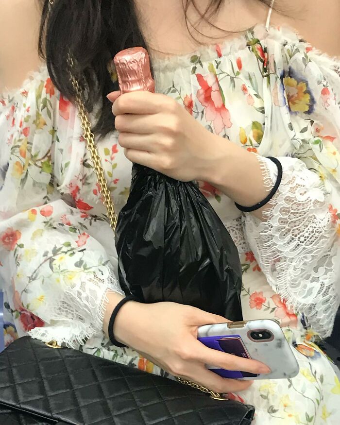 Person on New York subway holding a covered bottle and smartphone, showcasing unique items people carry in their hands.