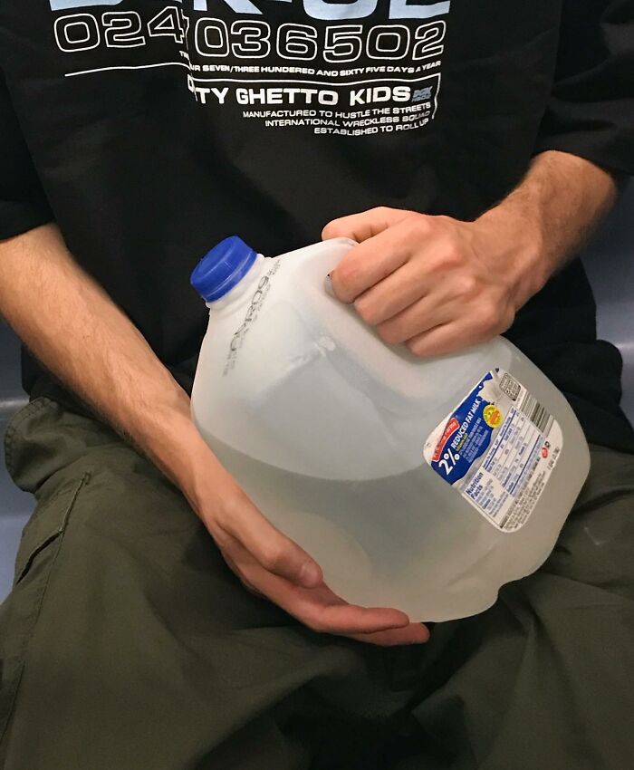 Person on New York subway holding a large milk jug, showcasing one of the weird items people carry in their hands.