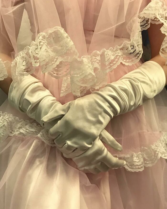 Person taking the subway in New York wearing satin gloves and holding delicate lace fabric with a pink dress background