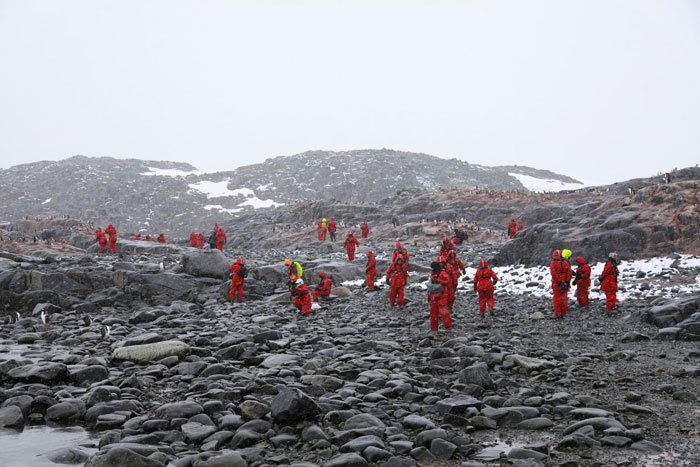 Researchers in red suits exploring rocky icy terrain as part of the 1831 mystery involving the sun turning blue.