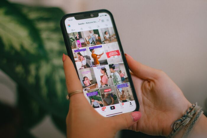 Person holding smartphone browsing TikTok videos about absurd relationship dealbreakers shared by women.