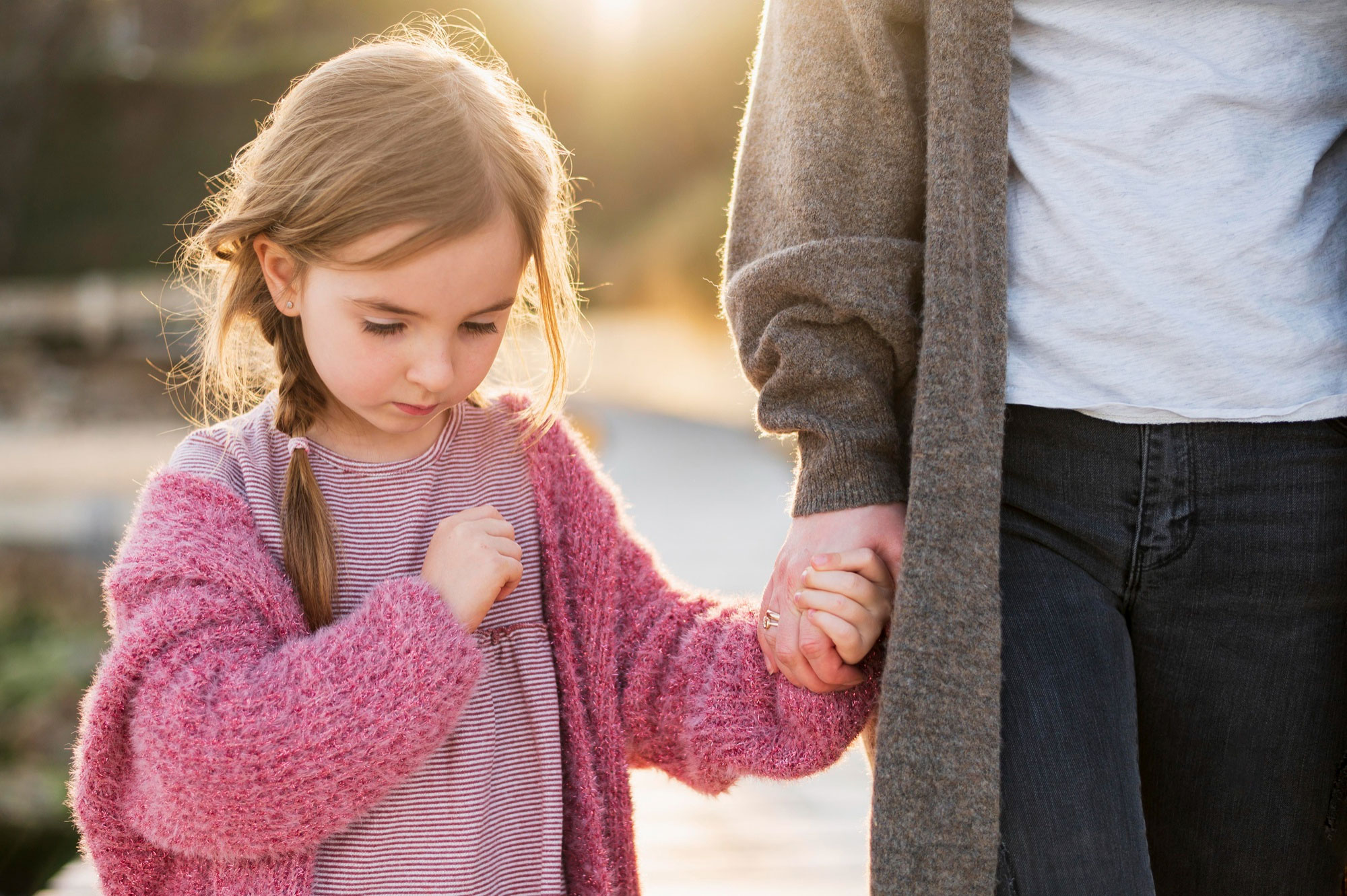 Young girl holding parent’s hand, looking down with a sad expression, representing male swim teacher and modest swimwear issue. Young girl holding parent’s hand, looking down with a sad expression, representing male swim teacher and modest swimwear issue.