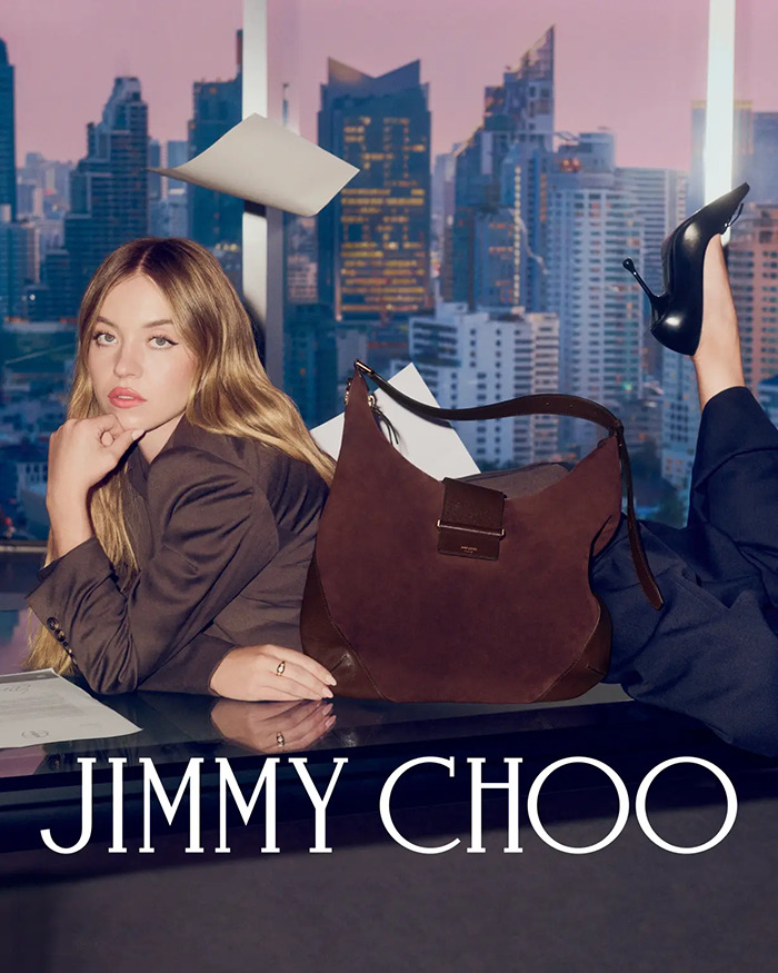 Sydney Sweeney posing with Jimmy Choo handbag and black heels against cityscape backdrop in fashion advertisement. Sydney Sweeney posing with Jimmy Choo handbag and black heels against cityscape backdrop in fashion advertisement.