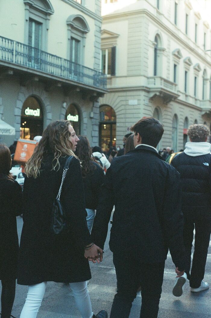 Couple holding hands walking in a crowded city street, illustrating people who were villains in someone else’s story.