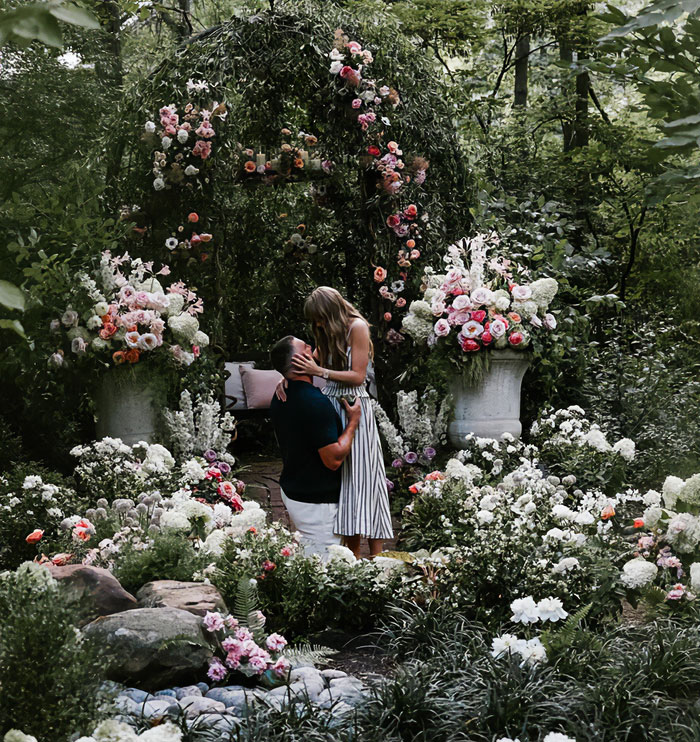 Couple sharing romantic moment in garden surrounded by flowers, illustrating mom telling 6YO daughter about Taylor Swift wedding.