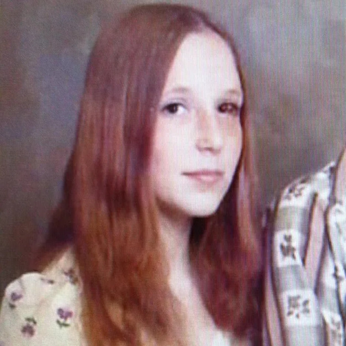 Teen with long red hair wearing a floral shirt, representing a survival story in a homicide serial spree escape.