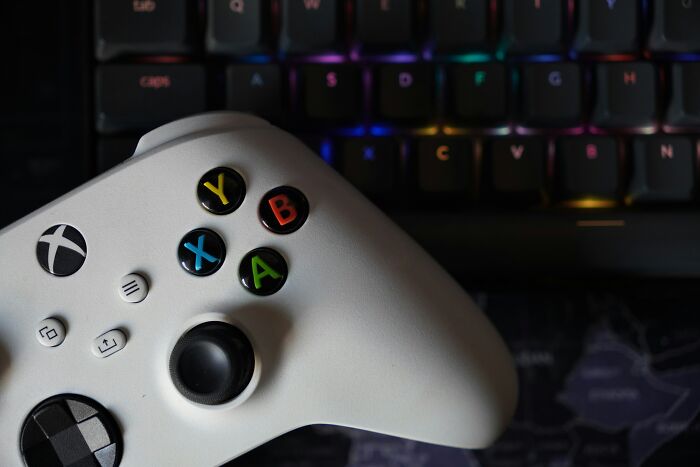White gaming controller with colorful buttons on a keyboard background illustrating product sabotage examples by companies