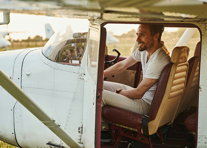 Man sitting inside small plane cockpit, illustrating guy refusing to let obese family fly in his plane, causing family drama. Man sitting inside small plane cockpit, illustrating guy refusing to let obese family fly in his plane, causing family drama.