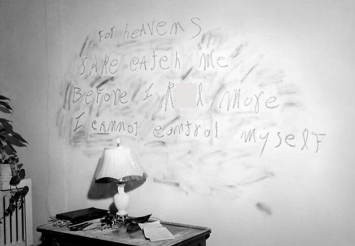 Handwritten chilling message on a wall above a desk in a dim room, part of terrifying photos and stories collection.