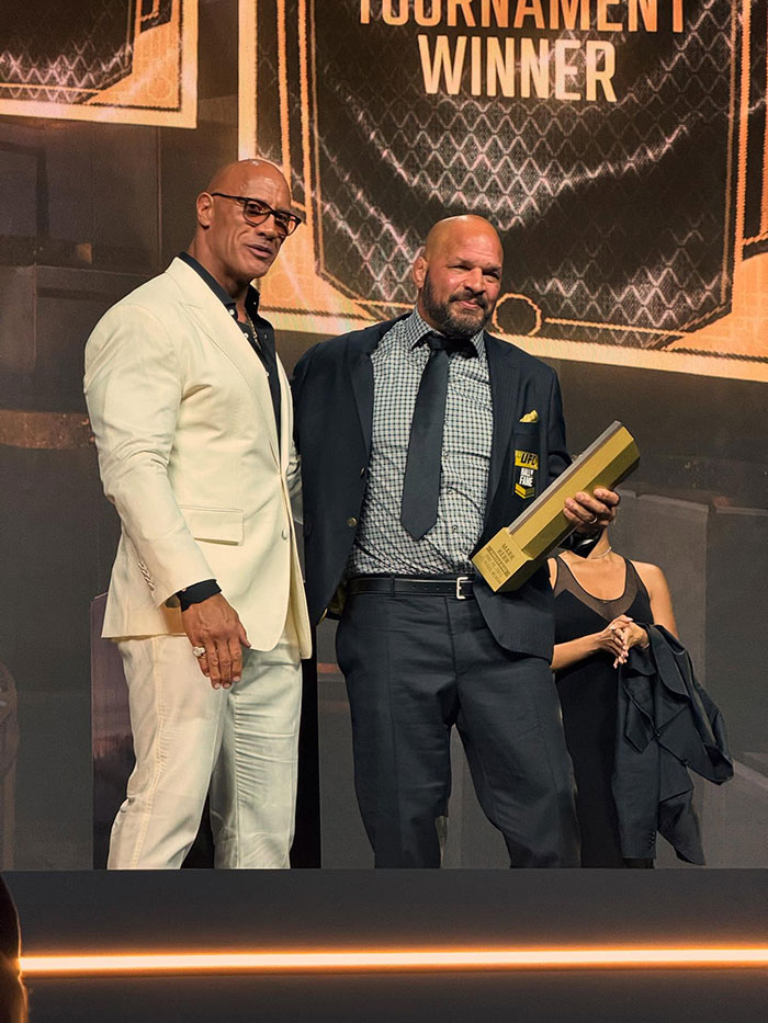 Dwayne Johnson in a white suit at an event with a man holding a UFC award, fans discuss actor&rsquo;s new slim look and health.