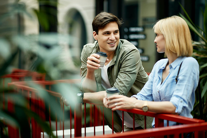 Young man and woman enjoying coffee outdoors, illustrating things that look awesome in movies but are terrible in real life.