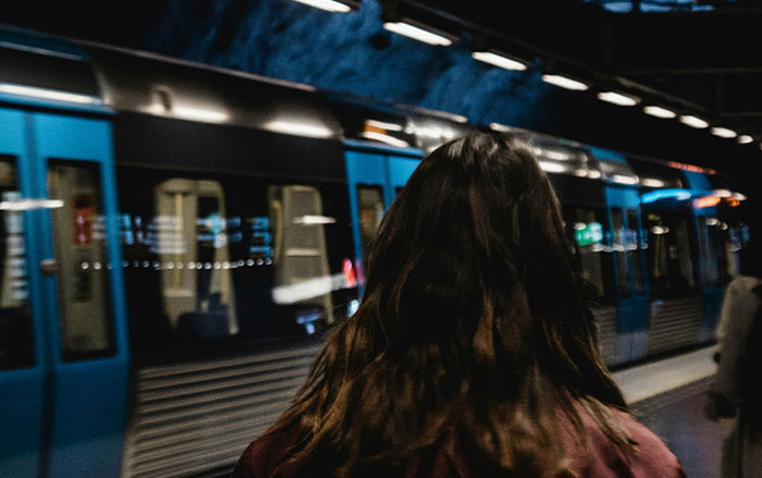 Woman with long hair standing on a subway platform at night, illustrating actions that decide if women feel safe or threatened.