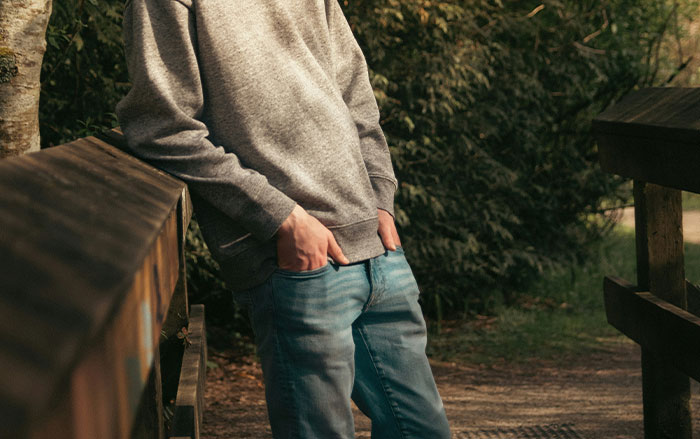 Man standing outdoors by wooden railing with hands in pockets illustrating things men do that impact women feeling safe or threatened
