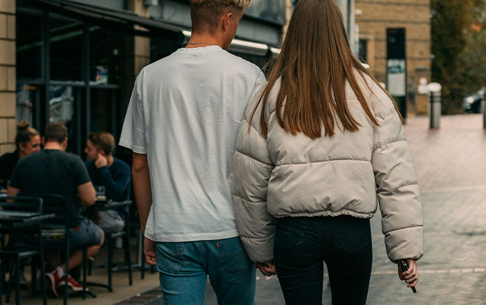 Young couple walking outdoors, illustrating subtle behaviors men do without realizing that affect women's sense of safety.