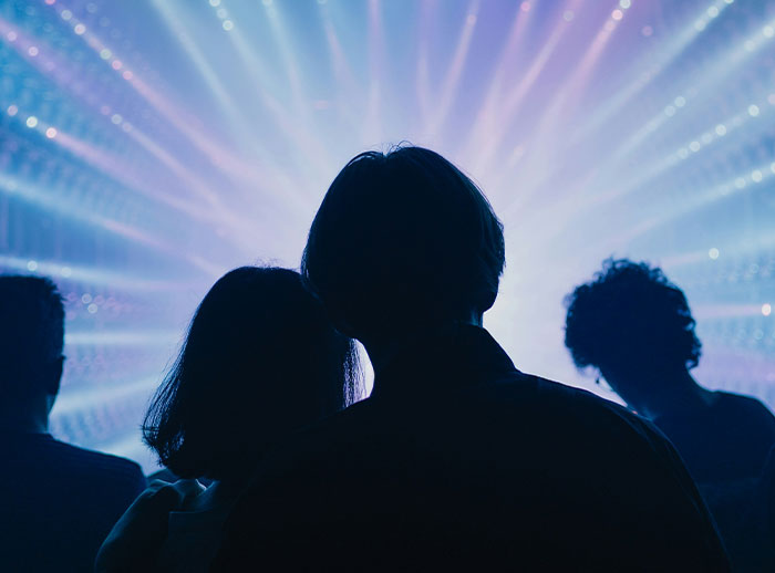 Silhouettes of men and women in dim light illustrating things men do affecting if women feel safe or threatened in social settings.