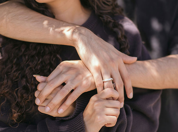 Close-up of a man gently holding a woman’s hands, illustrating things men do that make women feel safe or threatened.