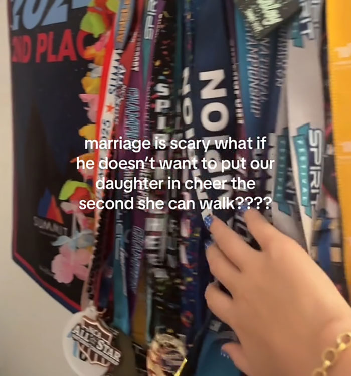 Hand reaching for colorful medals hanging on wall with text about marriage and cheerleading parenting fears.