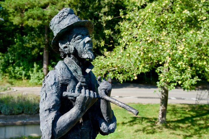 Statue of a man playing a flute outdoors surrounded by trees, symbolizing unexplained mysteries from the dawn of the internet.