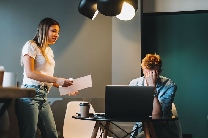 Young woman telling a frustrated man at a laptop one of the dumbest and most out of touch things people have been told