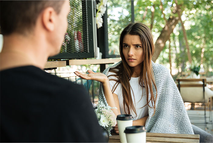 Young woman looks frustrated while a guy talks to her outdoors about dating because he is tall during a tense conversation.