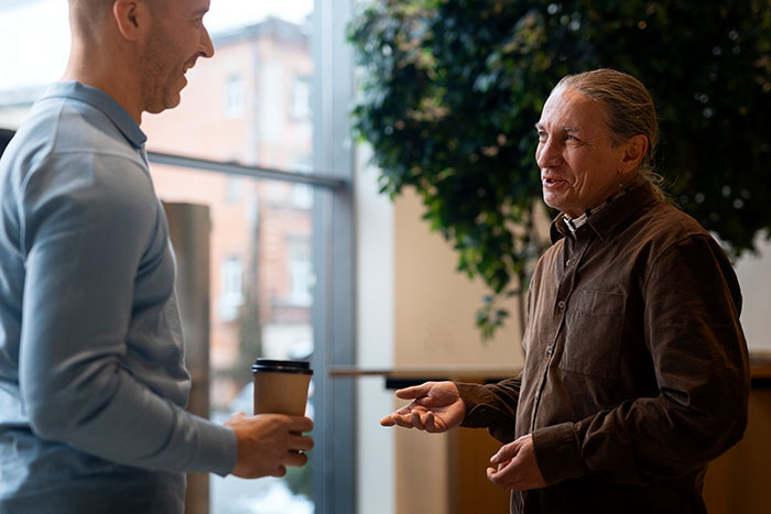 Two men having a casual conversation indoors, illustrating the impact of lies that changed someone else’s life.