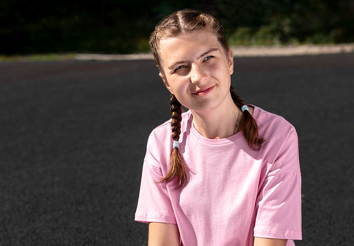 Young woman in pink shirt with braided hair smiling outdoors, reflecting on lies that changed someone else’s life.