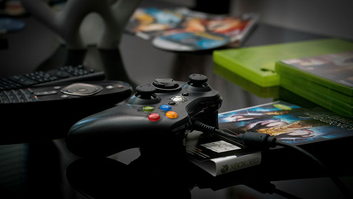 Xbox 360 controller with game discs and cases on a table, highlighting lies that changed someone’s life for better or worse.
