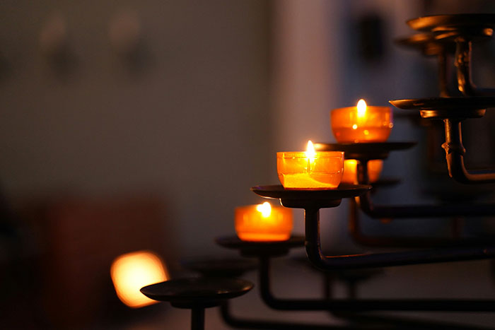 Orange candles lit on a dark metal holder, symbolizing the impact of lies that changed someone else’s life.