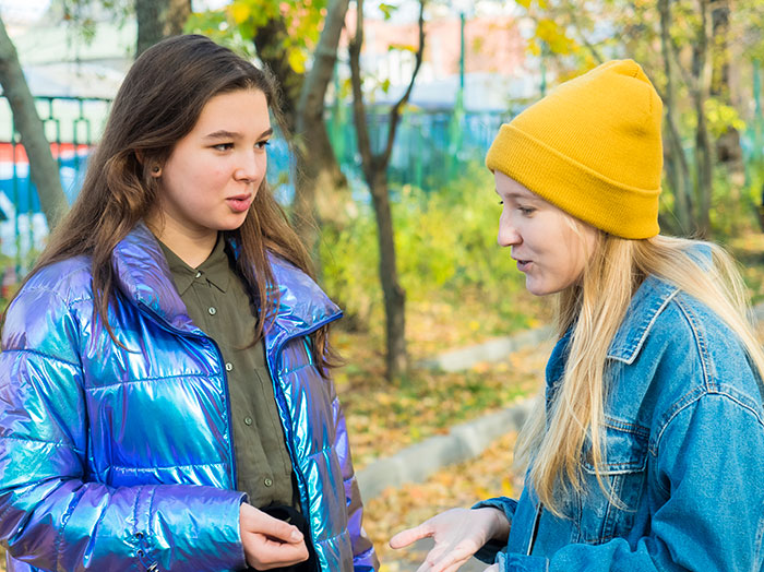 Two young women outdoors in autumn discussing 42 lies that changed someone else’s life for better or worse.