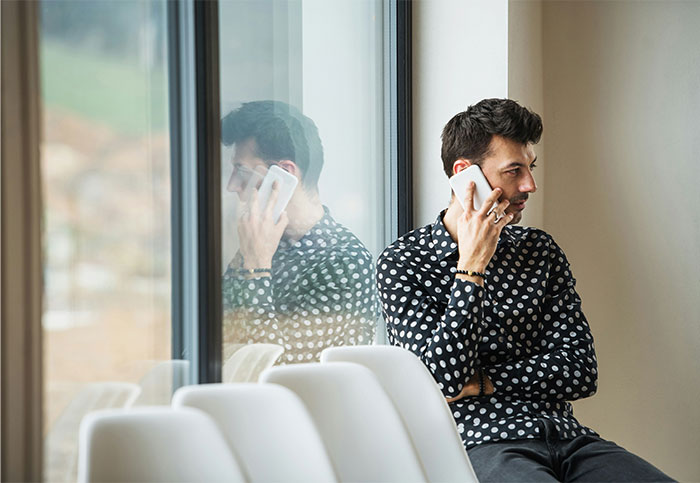 Man in a polka dot shirt looking concerned while making a phone call, symbolizing cheating and relationship issues.