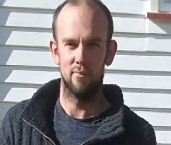Man standing outdoors in front of white siding, related to mom of kids who vanished into wilderness story.