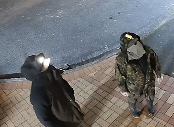 Two individuals dressed in dark outdoor clothing near a road, related to kids who vanished into wilderness case.