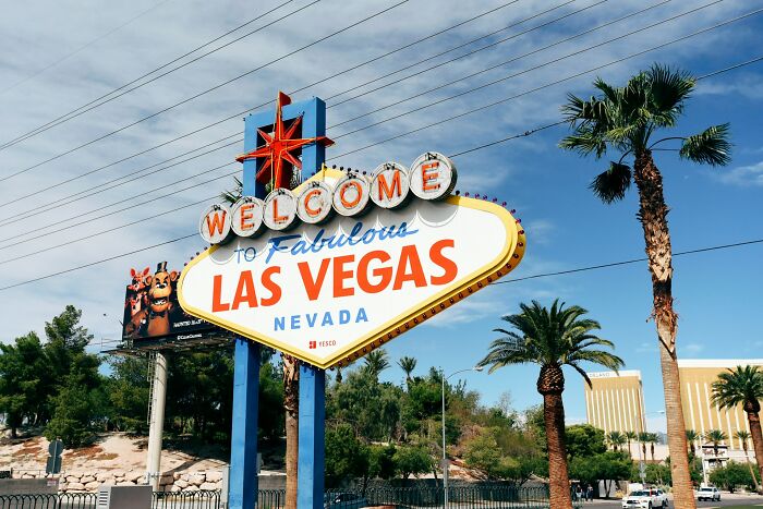 Welcome to Las Vegas sign under blue sky with palm trees, a travel destination seen differently in person.