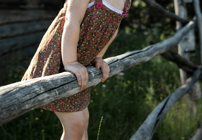 Child climbing over wooden fence in rural area, illustrating risky behavior tourists sometimes display seen by tour guides.