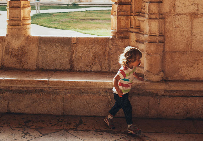 Young child walking inside an ancient stone structure, illustrating the challenges tour guides face with difficult tourists.