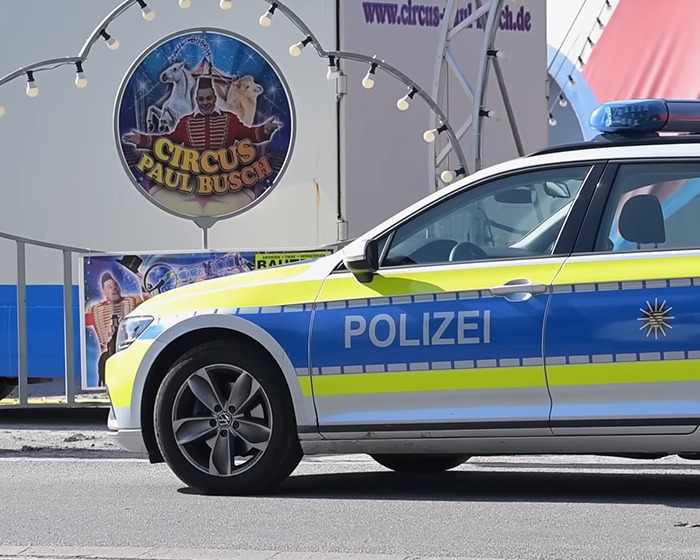 Police car parked outside Circus Paul Busch tent where trapeze artist lost life during circus stunt in front of families.