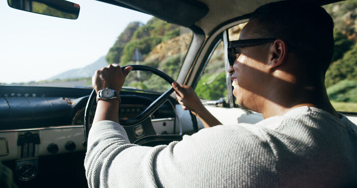 Man driving a vintage car on a sunny day, illustrating calm moments contrasted with doctors and nurses' haunting experiences.