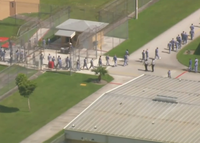Aerial view of detainees in uniforms walking within a secured facility linked to missing ICE detainee records.