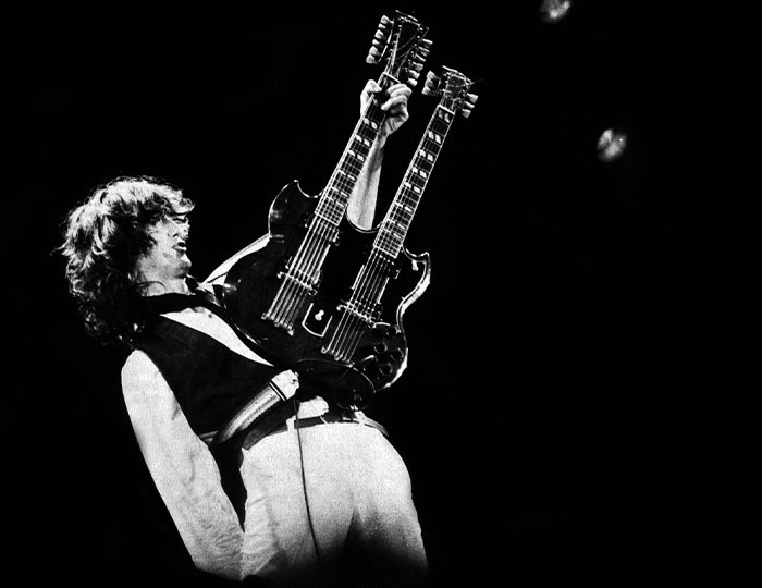 Black and white photo of a musician playing a double-neck guitar capturing a bizarre and fascinating historical moment.