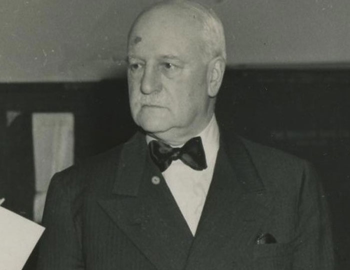 Black and white photo of an older man in a bow tie and suit, representing bizarre and fascinating historical events.